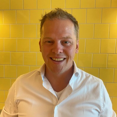 Glimlachende man voor een gele tegel muur