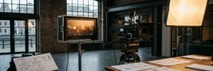 Professionele videomonitor met warm amber beeldmateriaal in een Amsterdamse filmstudio, omringd door een cinema camera en storyboard vellen.