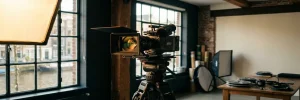 Professionele videocamera op statief in een Amsterdams studio, verlicht door warm ambergekleurd licht met softbox op de achtergrond.