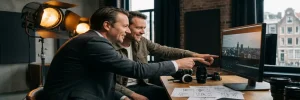 Videodirecteur en B2B-klant in pak bekijken footage op professionele monitor in Amsterdams studio, camera-apparatuur en storyboards zichtbaar.