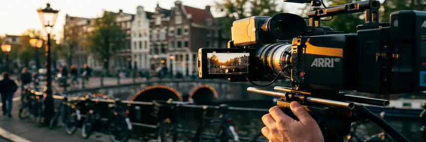 Cameraman filmt Amsterdamse gracht door bioscooplens tijdens het gouden uur, met warme amber- en dieptealtinten.