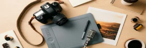 Professionele camera, grafisch tekentablet, microfoon en afgedrukte foto als flat lay op wit studio bureau.