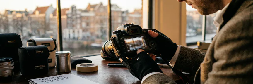 Fotograaf bekijkt behind-the-scenes opnames op camera-LCD in Amsterdam-studio, warme gouden-uurbelichting met zachte stadsachtergrond.