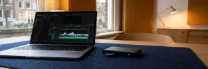 Laptop met videotijdlijn naast geheugenkaartlezer op een opgeruimd bureau in een Amsterdams videobewerkingsstudio.